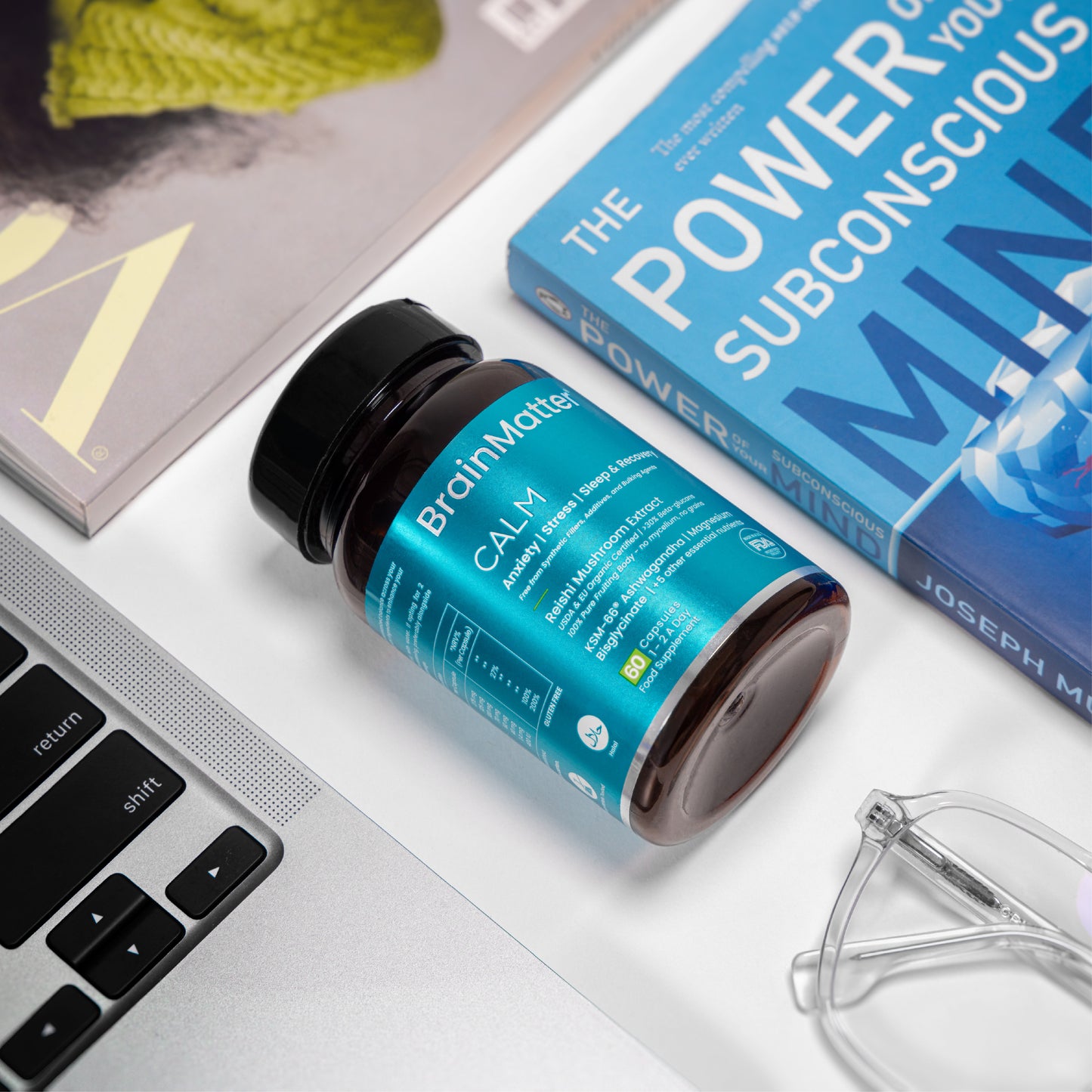 BrainMatter Calm on a work desk beside books and glasses — a lifestyle image promoting stress relief and mental reset.