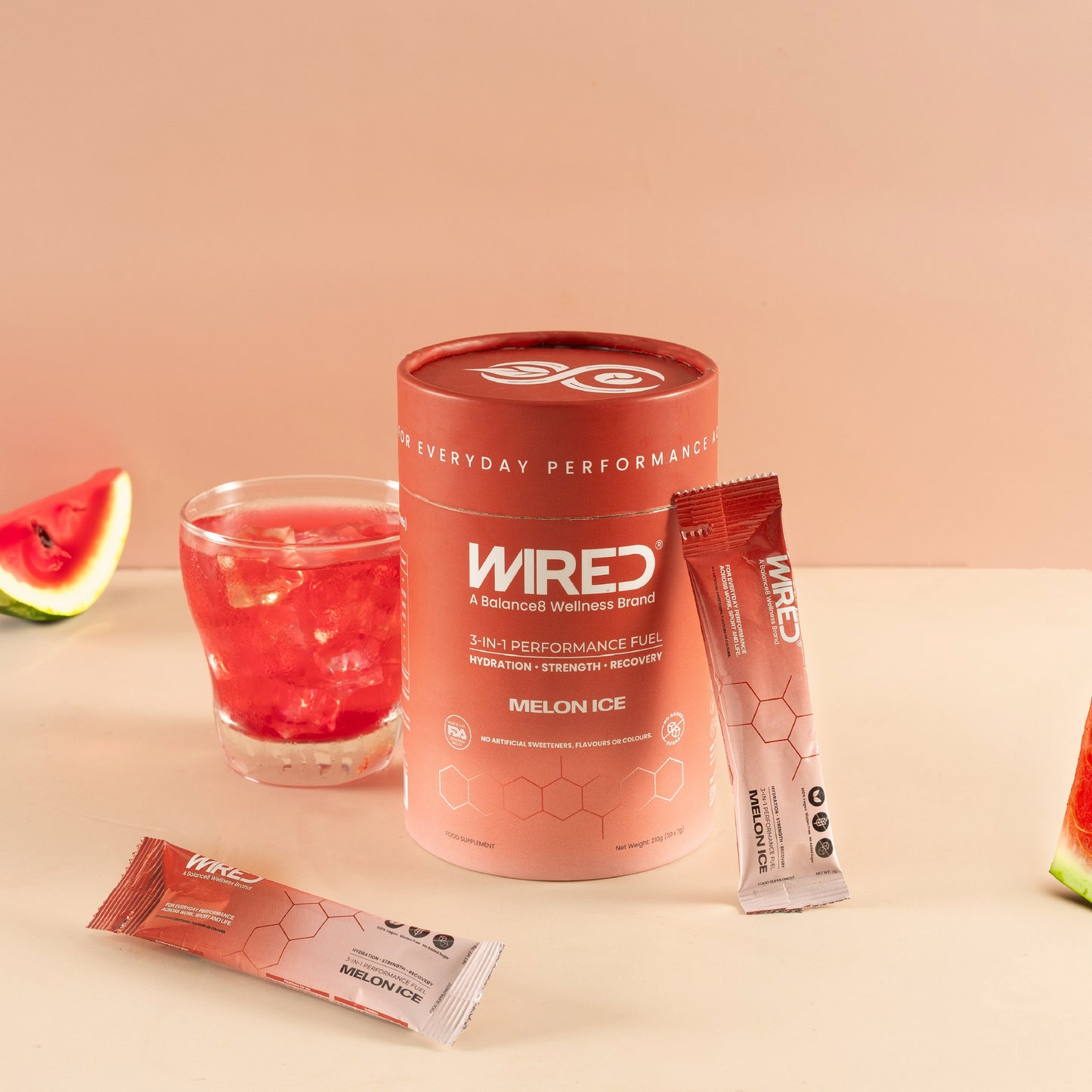 WIRED Melon Ice – lifestyle shot of red tub, sachets and mixed drink with watermelon slices | Balance8 Wellness