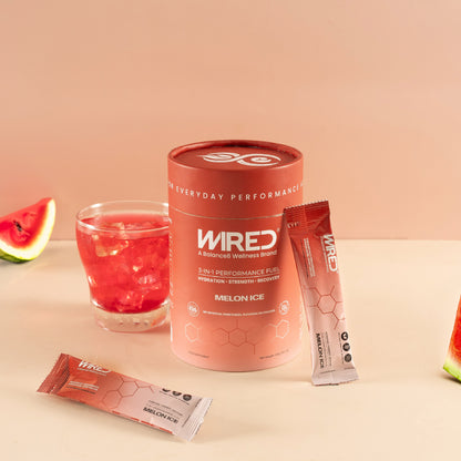 WIRED Melon Ice – lifestyle shot of red tub, sachets and mixed drink with watermelon slices | Balance8 Wellness