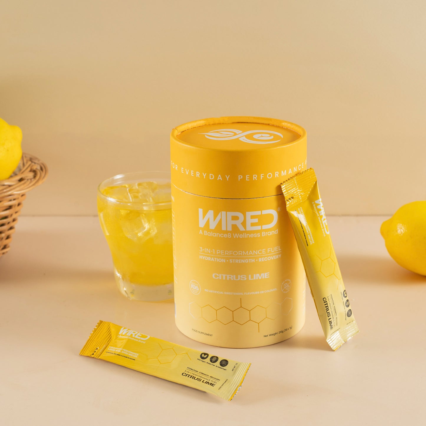 WIRED Citrus Lime – lifestyle shot of yellow tub, sachets and mixed drink with lemons | Balance8 Wellness